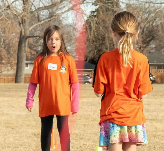 young girl wearing an orange soccer jersey is excited while playing soccer